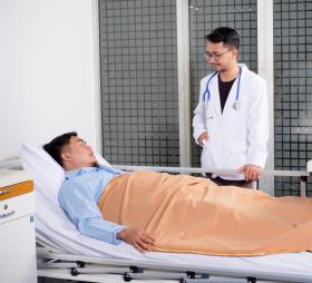 Doctor standing beside patient's hospital bed